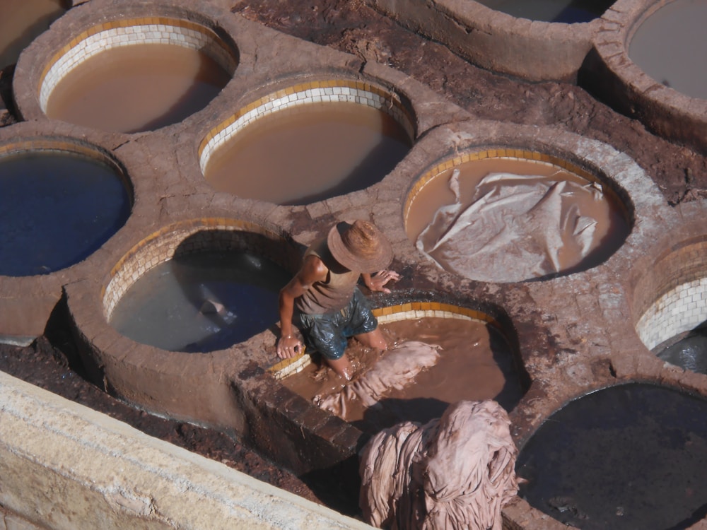 Tannery worker standing among colourful dye vats — traditional leather tanning